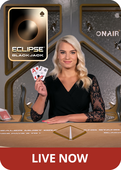 Female game presenter behind a Blackjack table, holding up 2 cards near a logo of Eclipse Blackjack, reading 'Live Now'.