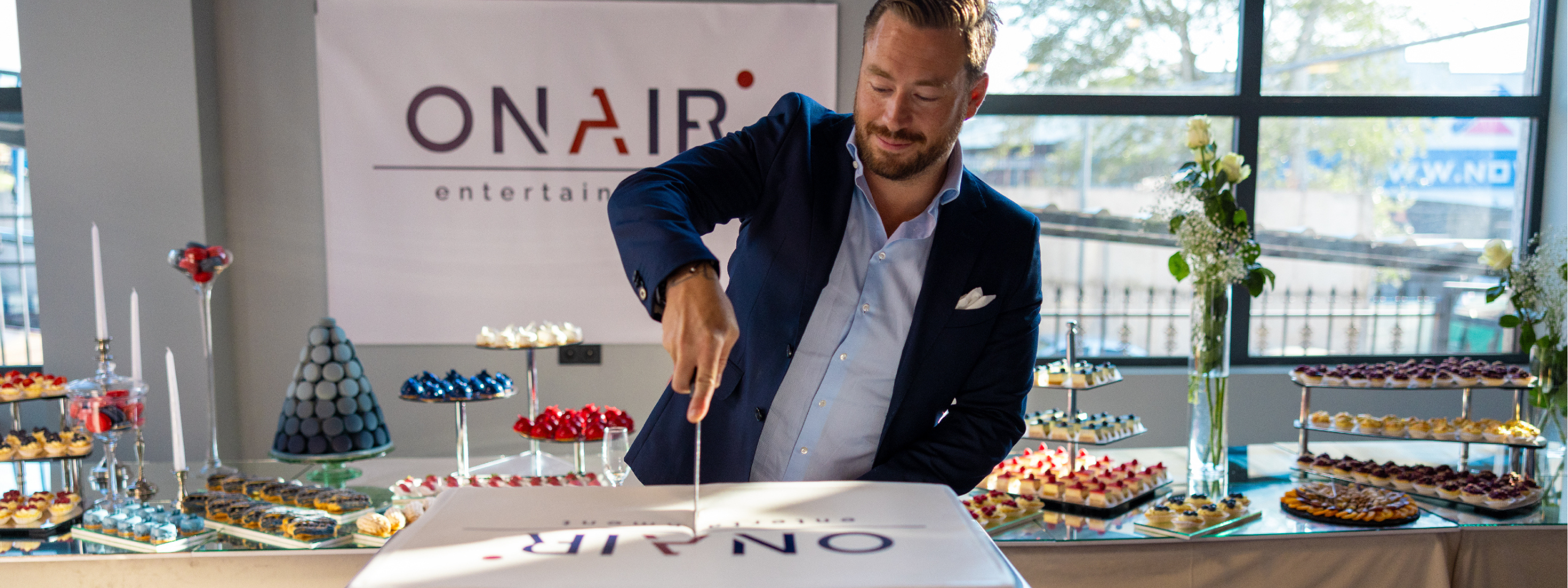 Photo of OnAir Entertainment's CEO, Andres Rengifo cutting a cake in celebration of the studio opening in Tibilsi, Georgia.